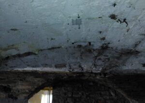 R1 Rissmonitor über einem Riss an einer Betonwand in einem Kellerraum installiert